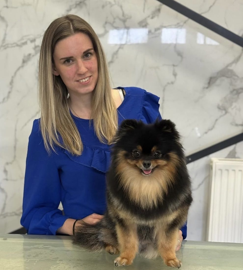 Stacey with a freshly groomed Pomeranian on the grooming table